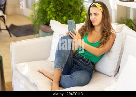 High angle view of biracial young woman taking selfie with smart phone while relaxing on sofa Stock Photo