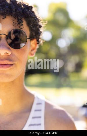 Close-up portrait of confident biracial young man wearing sunglasses in yard on sunny day Stock Photo