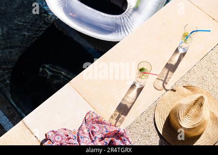 High angle view of lemonade glasses with dress and hat at poolside, copy space Stock Photo