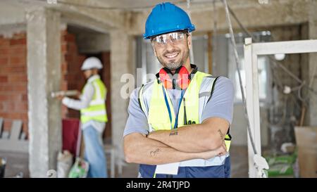 Two men builders standing with arms crossed gesture working at construction site Stock Photo