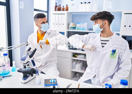 Two man scientists doing elbow greeting at laboratory Stock Photo