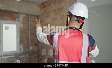 Young latin man builder talking on smartphone at construction site Stock Photo