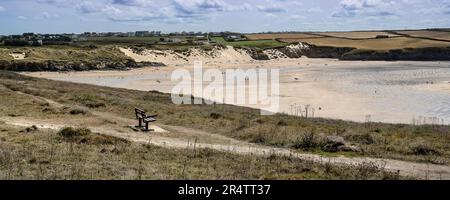 A panoramic image of a bench on the coast path overlooking the award winning Crantock Beach in Newquay in Cornwall in the UK. Stock Photo
