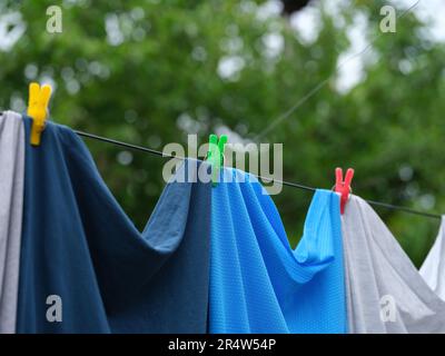 Clothes hanging on a clothes line with colorful clothes pins. Close up. Stock Photo