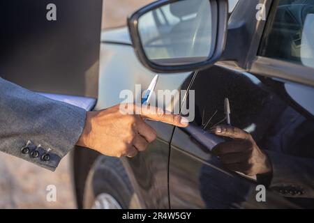 Detail of a hand of a insurance agent pointing out a scratch on a car. Stock Photo