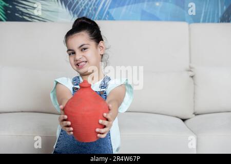 Kid showing her Piggy towards the camera with happy expression. investment concept Stock Photo