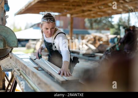 Woman working with wooden planks in a sawmill Stock Photo