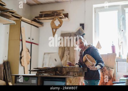 Female carpenter using laptop in a carpentry workshop Stock Photo