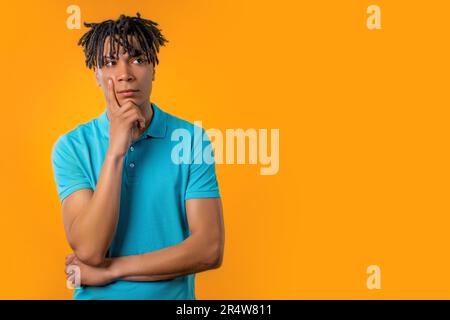 Thinking puzzled man on yellow background. Guy looking for answer, copy space Stock Photo
