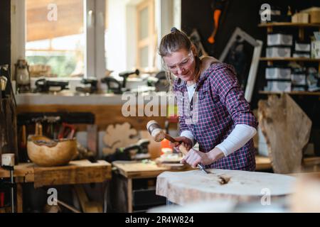 Craftswoman working with wood in carpentry workshop Stock Photo