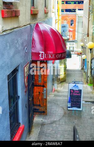 The Duke of Duckworth Street Club or Bar is in an alley in downtown St. John's. The entrance to the restaurant has a red vinyl awning and steps. Stock Photo