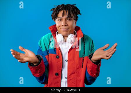 Confused young african man, shoulders up can't help, makes gesture of dont know Stock Photo