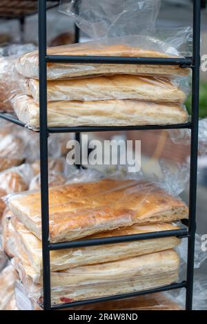 A stack of traditional Italian rosemary garlic focaccia bread on a black metal display. The airy square flatbread is covered in olive oil and garlic. Stock Photo