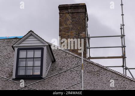 A vintage double hung window and dormer on a beige colored exterior cedar roof of an old building. The windows are black with white trim. Stock Photo
