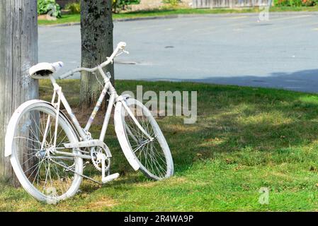 An adult bike painted white as a memorial site for a previous bicycle crash. The ghost bike is a symbol of memory and a reminder to share the road. Stock Photo