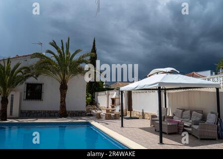 Storm clouds approaching a Spanish villa still in sunlight. Rain on the way Stock Photo