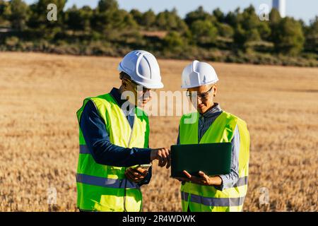 Engineers using a laptop while working together in the field. Stock Photo