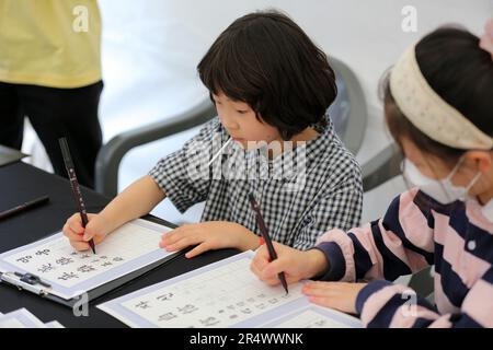 Seoul, South Korea. 30th May, 2023. Children experience calligraphy during the Trilateral Cooperation Secretariat (TCS) Day event in Seoul, South Korea, May 30, 2023. The TCS is a Seoul-based international body for promoting peace and common prosperity among China, Japan and South Korea. Various activities were held on Tuesday by the TCS to commemorate the 13th anniversary of the signing of an agreement on its establishment. Credit: Wang Yiliang/Xinhua/Alamy Live News Stock Photo