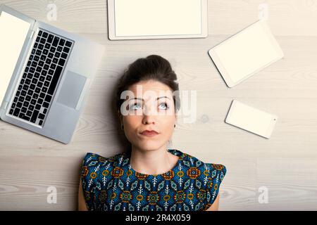 Web writing professional surrounded by devices, looks doubtful. Seems all her ideas are taken, AI is faster Stock Photo