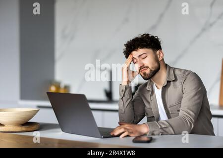 Bad news, lack of understanding of new app, info overload, device malware concept. Young man in glasses sit at table looks at laptop screen touch fore Stock Photo