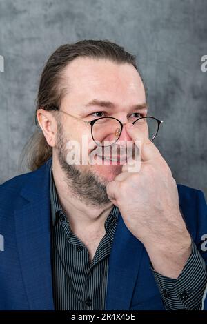 One man in a blue jacket adjusts his glasses Stock Photo