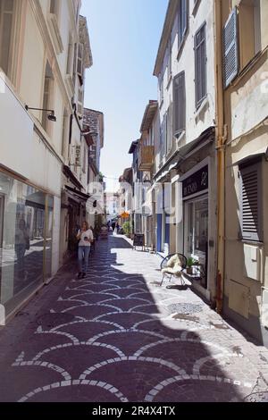 France, Provence-Alps, Cote d'Azur, Antibes, Narrow side street in the old town busy with shoppers. Stock Photo