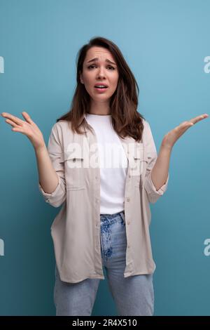 confused brunette young brunette lady dressed in shirt and jeans Stock Photo