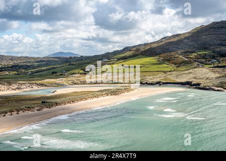 Scenic view of the turquoise waves of the Atlantic lapping the sandy shore of the beach at Barleycove with the hills and farmland of the countrysid... Stock Photo