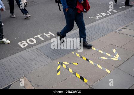 Remnants from the Covid pandemic are seen on the pavement next to stencil lettering for Both Ways crossing on Blackfriars Bridge Road in Southwark, south London, on 23rd May 2023, in London, England. Stock Photo