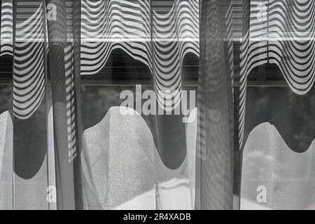 Abstract pattern formed by window shades and sheer curtain Stock Photo