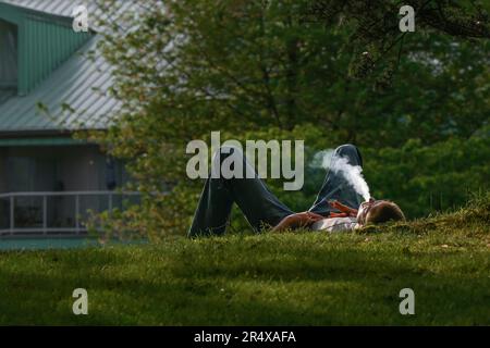 relaxed, reclining young man smoking cigarette and blowing smoke Stock Photo