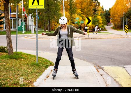 Teenage girl inline skating in a city park during a warm fall day; St. Albert, Alberta, Canada Stock Photo