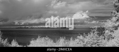 Dramatic cloud formation over rocks in Lake Superior in infrared; Thunder Bay, Ontario, Canada Stock Photo