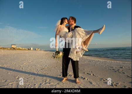 Bride and groom kiss on a beach in Florida; Panama City Beach, Florida, United States of America Stock Photo