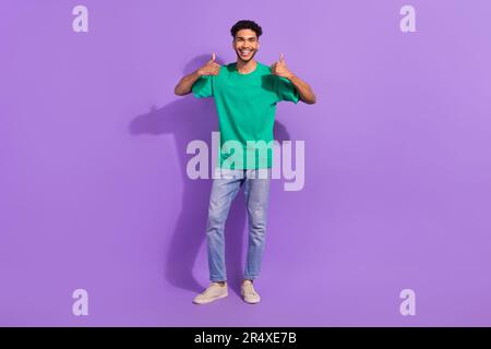 Full body cadre of positive man wear green t-shirt thumbs up high quality clothes from aliexpress isolated on violet color background Stock Photo
