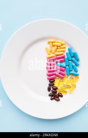 Food supplements-capsules of bright color lie on a white plate in a heap. Concept of medicine and health Stock Photo