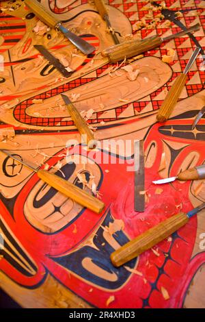 Tlingit painted panel and wood carving tools in Saxman Totem Park, Ketchikan, Alaska, USA; Ketchikan, Alaska, United States of America Stock Photo