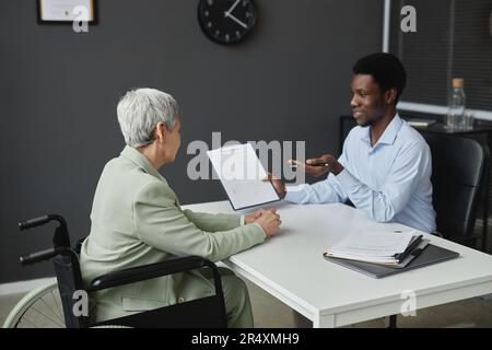 Portrait of smiling HR recruiter speaking to senior woman with disability in job interview Stock Photo