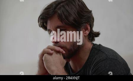 One preoccupied young man thinking deeply about life problematic issues. Worried male person in 30s with hand in chin with thoughtful expression Stock Photo