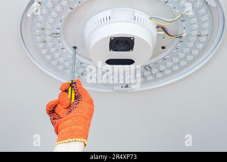 An electrician installs a chandelier on the ceiling. Stock Photo