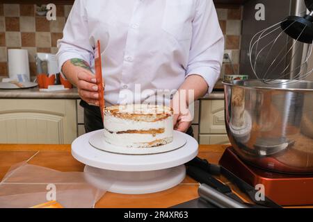 cheerful girl using a smooother while baking cake in the kitchen Stock Photo