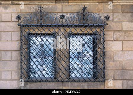 Two rectangular windows. Closed with a figured iron lattice on the background of a stone wall. From the Windows of the world series. Stock Photo