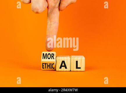 Ethical or moral symbol. Businessman turns wooden cubes and changes the word Ethical to Moral on a beautiful orange table orange background. Business Stock Photo