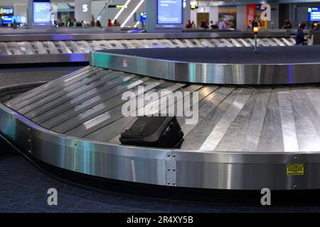 A suitcase on a luggage carousel at an airport arrivals baggage claim area. Stock Photo