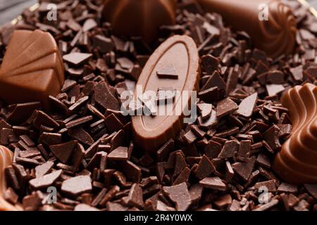Beautifully shaped milk chocolate sweets dipped in chocolate chips close-up, chocolate candy making concept, chocolate background. Stock Photo