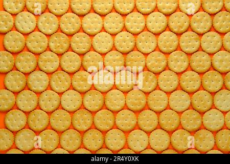 Round crackers in repeating rows against a plain background. Top-down view. Stock Photo