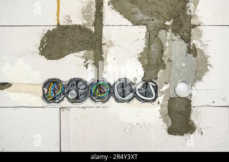 Boxes with cables for electric sockets installed in new house building empty wall Stock Photo