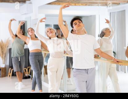Diligent young man doing choreography at ballet barre Stock Photo