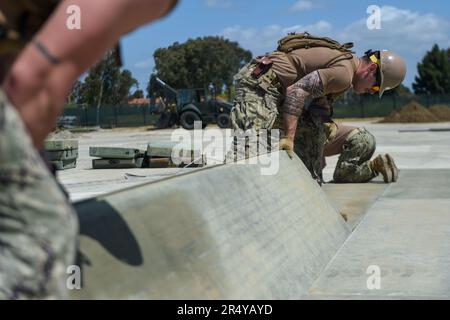 PORT HUENEME, Calif. (May 10, 2023) Sailors assigned to Naval Mobile Construction Battalion (NMCB) 4 set down metal paneling  to practice their airfield damage repair skills. NMCB 4 is currently conducting Field Training Exercise Turning Point to become the ready-to-deploy battalion for the Indo-Pacific Command area of responsibility. (US Navy photo by Mass Communication Specialist 2nd Class Dakota Rayburn) Stock Photo