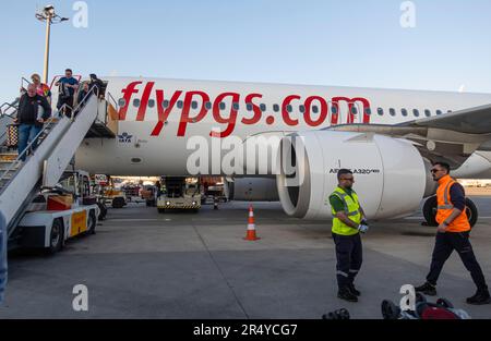 Passengers leaving Pegasus airlines airplane on tarmac on stairs, employees on tarmac. Sabiha Gokcen airport Istanbul Turkey Stock Photo